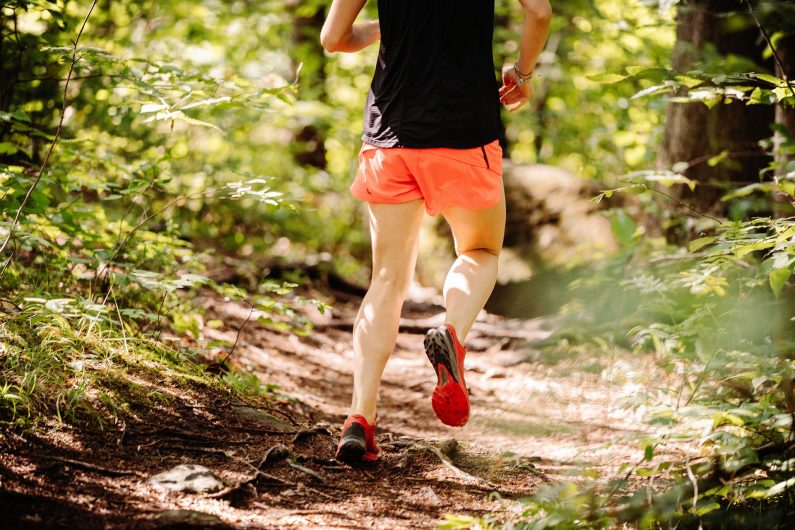 L’image représente un personne en train de courir en forêt.